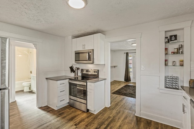 kitchen with dark wood-style floors, dark countertops, a textured ceiling, white cabinets, and appliances with stainless steel finishes