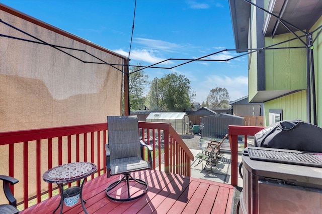 deck featuring an outdoor structure, a storage unit, a fenced backyard, and grilling area