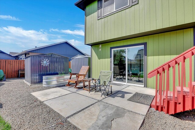 view of patio / terrace with fence, an outdoor structure, and a shed