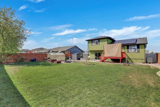 view of yard featuring central AC unit, an outdoor structure, a patio area, a greenhouse, and a fenced backyard