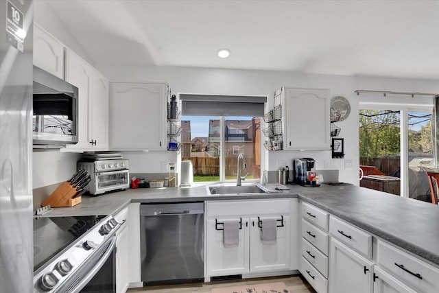 kitchen featuring recessed lighting, a sink, a toaster, white cabinets, and appliances with stainless steel finishes