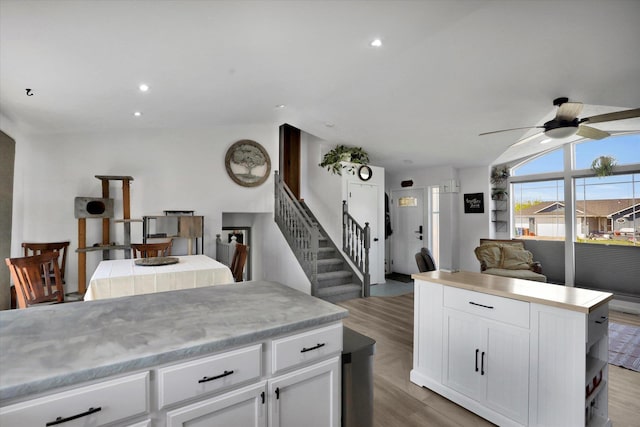 kitchen featuring open floor plan, a ceiling fan, light wood-style flooring, and light countertops