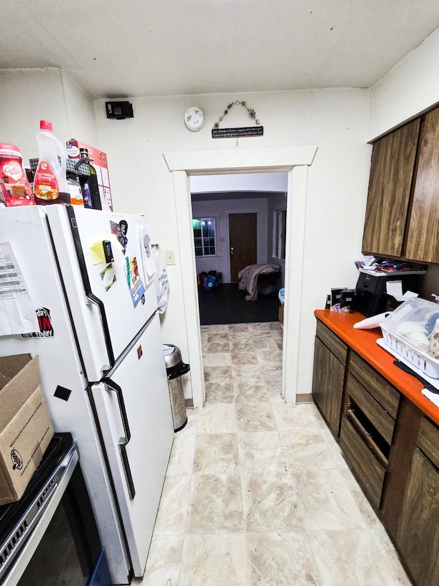 kitchen featuring freestanding refrigerator and dark brown cabinets