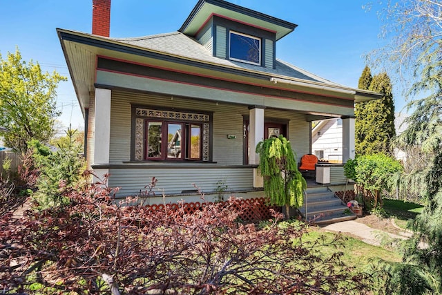 bungalow featuring a chimney, a porch, and cooling unit