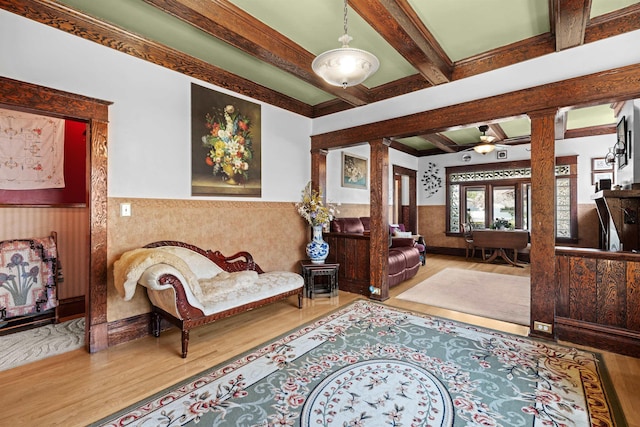 living area with beamed ceiling, coffered ceiling, ornate columns, wainscoting, and wood finished floors