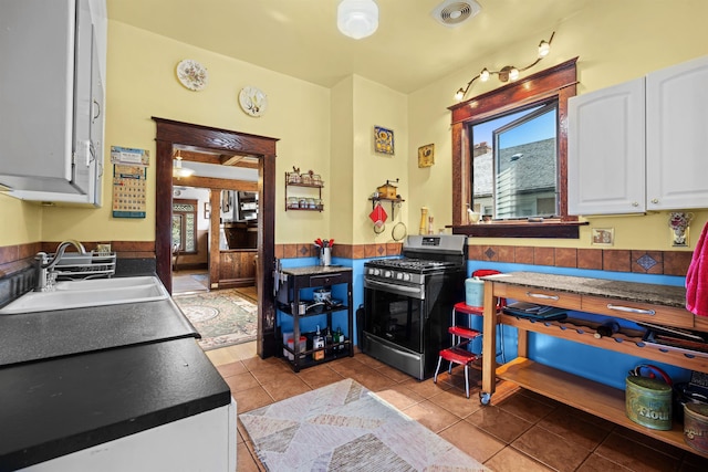 kitchen featuring white cabinets, a sink, visible vents, stainless steel gas range, and tile patterned floors