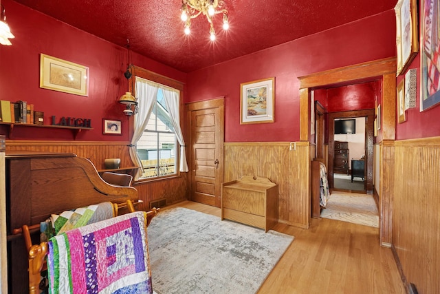bedroom featuring visible vents, wood finished floors, and a wainscoted wall