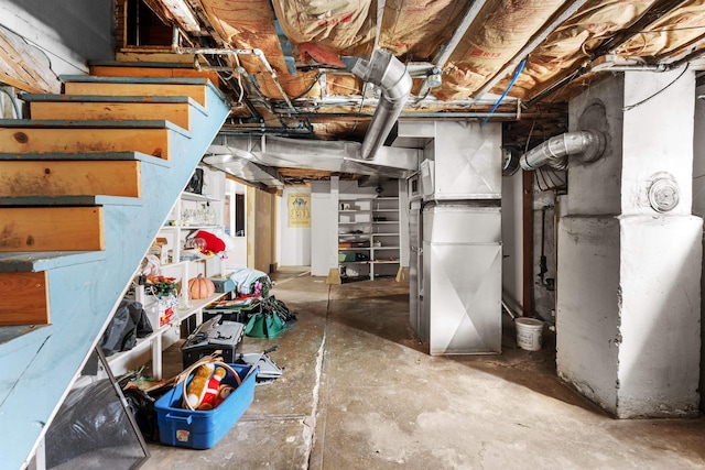 unfinished basement featuring stairs and heating unit