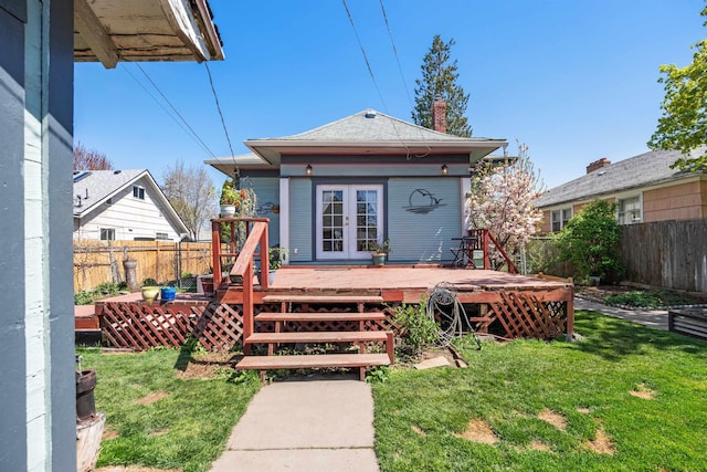 back of property with french doors, a fenced backyard, and a yard