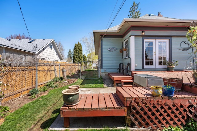 exterior space featuring a wooden deck, a fenced backyard, and french doors