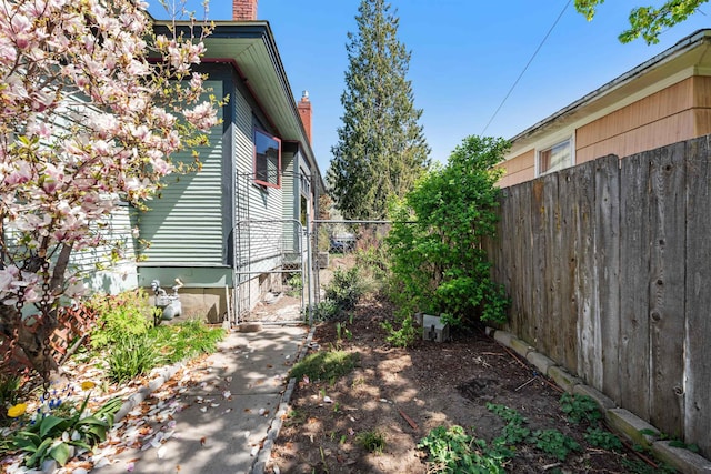 view of property exterior featuring fence, a chimney, and a gate