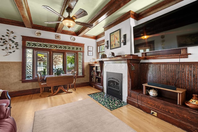 living area featuring baseboards, wood finished floors, a ceiling fan, and beamed ceiling