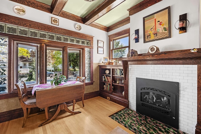 living area with beam ceiling, light wood-style floors, and a fireplace