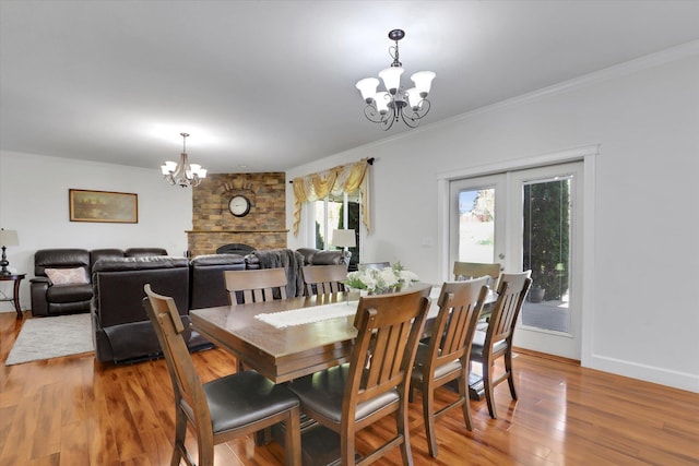 dining room with french doors, ornamental molding, an inviting chandelier, and wood finished floors