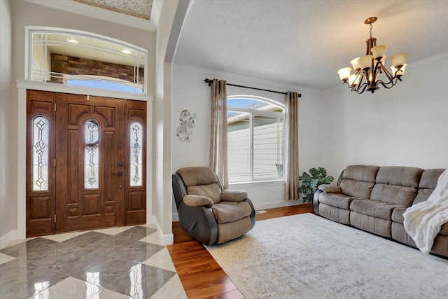 foyer featuring wood finished floors, a chandelier, crown molding, and baseboards