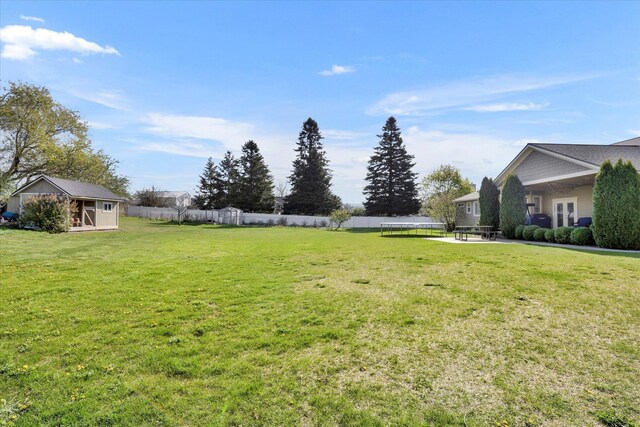 view of yard with fence, an outdoor structure, and french doors
