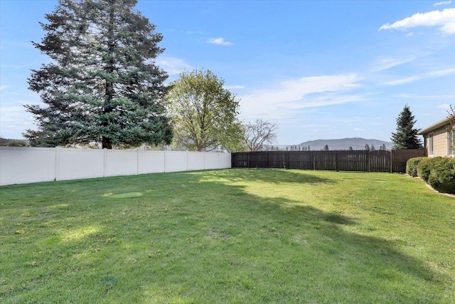 view of yard featuring a mountain view and a fenced backyard