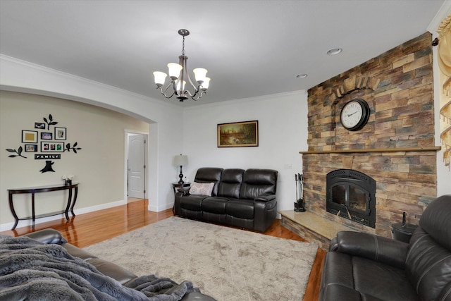 living room with ornamental molding, arched walkways, a notable chandelier, and wood finished floors