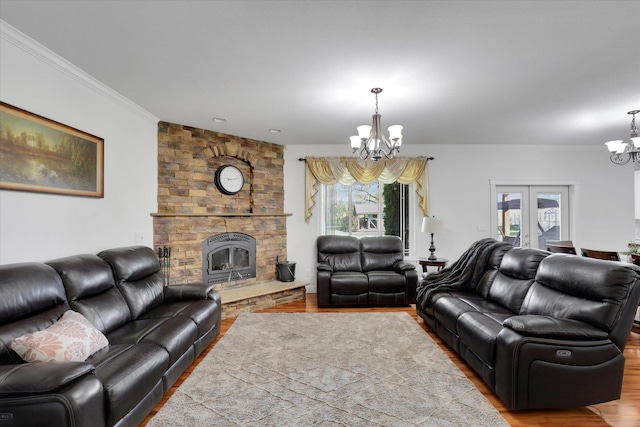 living room with wood finished floors, a stone fireplace, a notable chandelier, french doors, and crown molding