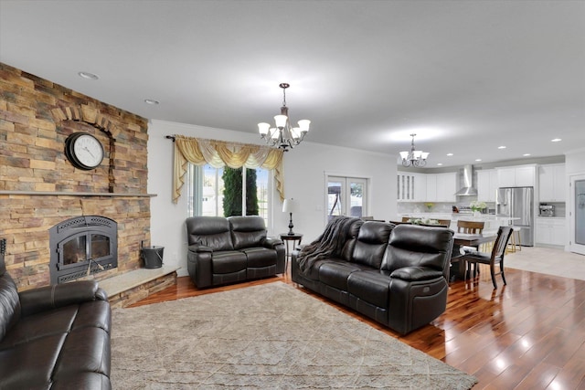 living room featuring an inviting chandelier, light wood-type flooring, crown molding, and recessed lighting