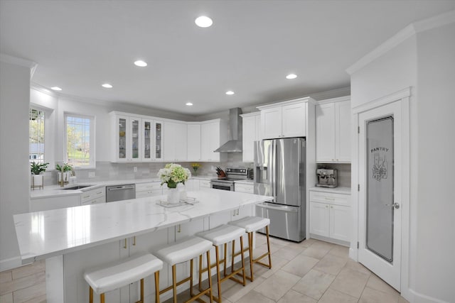 kitchen featuring wall chimney range hood, stainless steel appliances, ornamental molding, and a sink