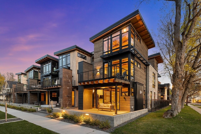 rear view of property with an outdoor hangout area, a patio, a yard, and a balcony