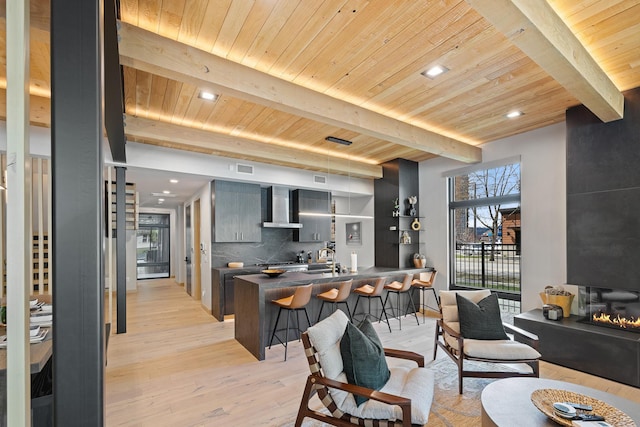 living room featuring beamed ceiling, light wood-style flooring, and wood ceiling