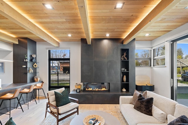 living area featuring wooden ceiling, wood finished floors, a tile fireplace, recessed lighting, and beamed ceiling