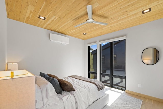 bedroom with a wall mounted air conditioner, a ceiling fan, baseboards, wood ceiling, and wood finished floors