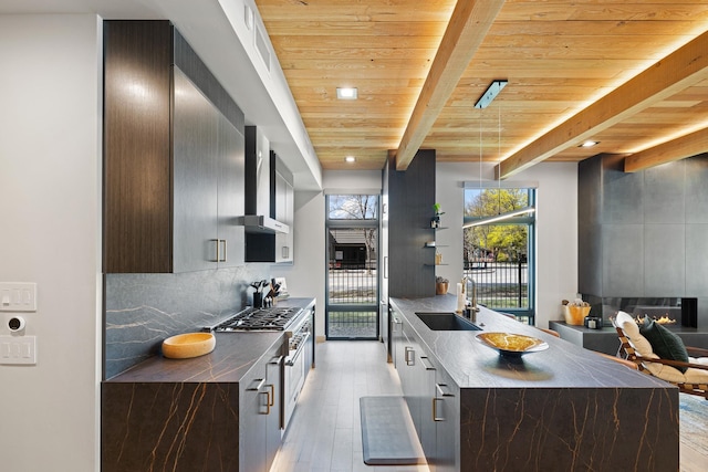 kitchen with modern cabinets, a sink, a fireplace, wall chimney range hood, and wood ceiling