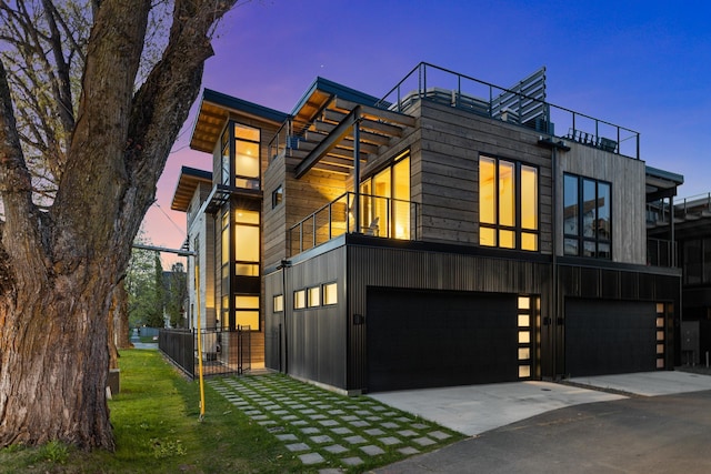 modern home featuring driveway, a balcony, and an attached garage