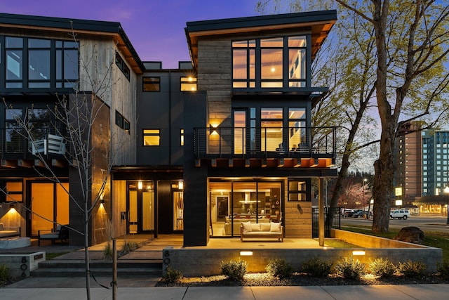 back of property at dusk featuring a balcony