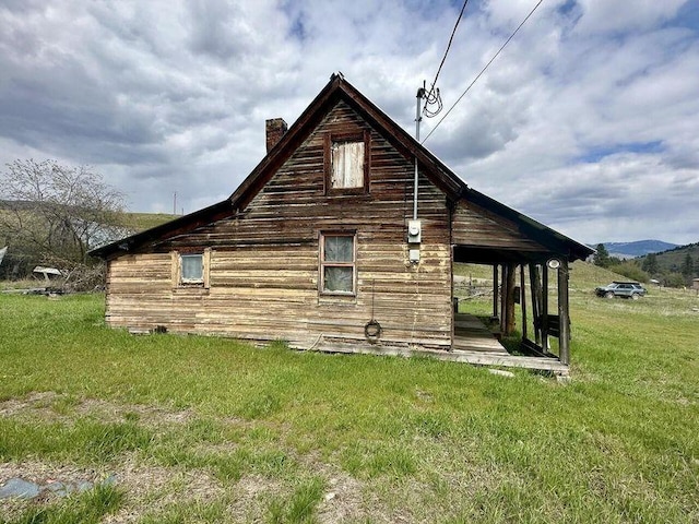 view of side of home with a chimney and a yard