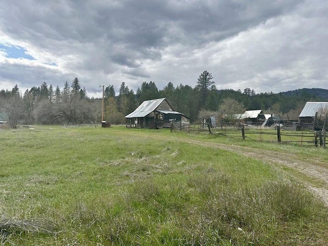 view of yard with an outbuilding, a rural view, a barn, and fence