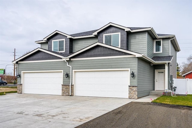 view of front facade with stone siding, fence, driveway, and an attached garage