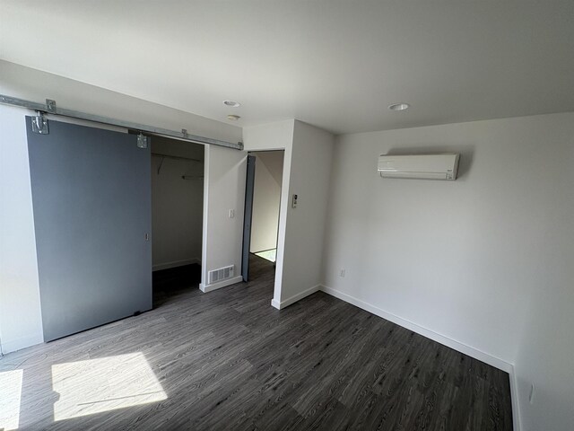 904 E Indiana Ave, Spokane, WA 99207 - unfurnished bedroom with a barn door, an AC wall unit, dark wood-style flooring, a closet, and recessed lighting