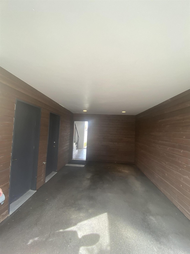 unfurnished room with wooden walls and concrete flooring