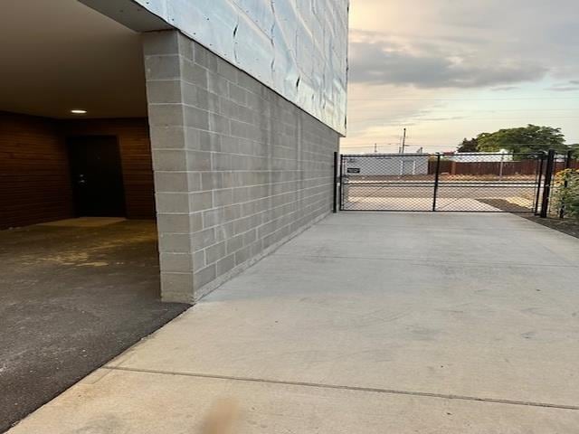 exterior space with concrete driveway, fence, a gate, and concrete block siding