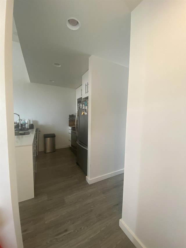 hallway with baseboards, a sink, and dark wood finished floors