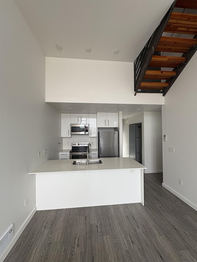 904 E Indiana Ave, Spokane, WA 99207 - kitchen with stainless steel appliances, a peninsula, dark wood-type flooring, and white cabinets