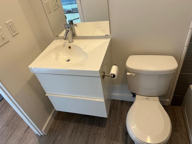 bathroom with toilet, baseboards, wood finished floors, and vanity