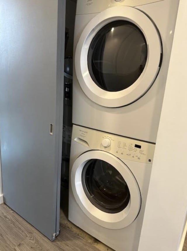 washroom with stacked washer and dryer, laundry area, and light wood-type flooring