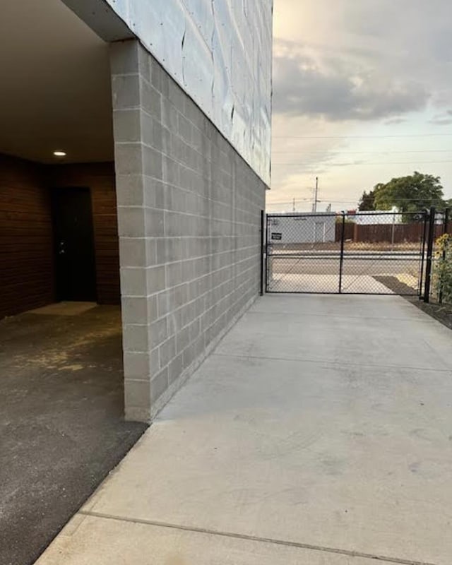 exterior space with a gate, concrete block siding, and fence