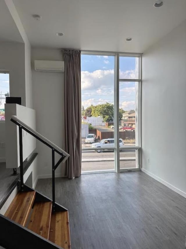 interior space featuring recessed lighting, baseboards, a wall unit AC, wood finished floors, and floor to ceiling windows