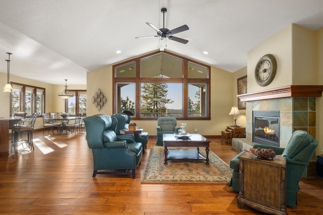 living area with wood finished floors, recessed lighting, a tile fireplace, a ceiling fan, and vaulted ceiling