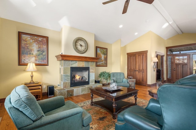 living area featuring wood finished floors, a fireplace, baseboards, lofted ceiling with beams, and a ceiling fan