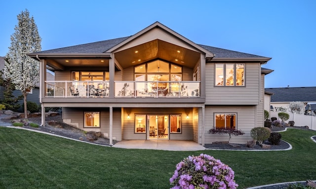 rear view of house featuring a lawn, a patio area, fence, and a balcony