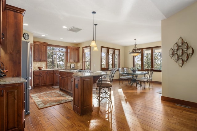 kitchen with visible vents, baseboards, a wealth of natural light, and a kitchen bar