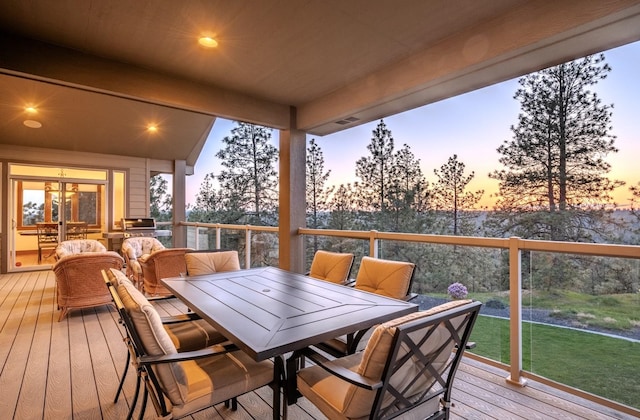 wooden terrace featuring outdoor dining area and a lawn