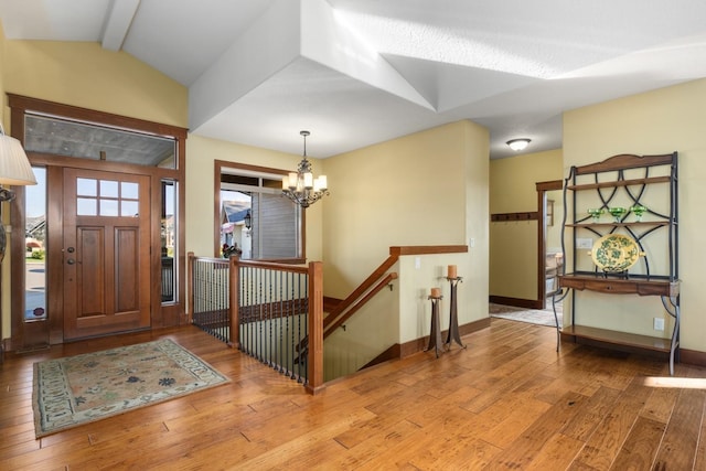 entryway with baseboards, a chandelier, lofted ceiling with beams, and hardwood / wood-style flooring
